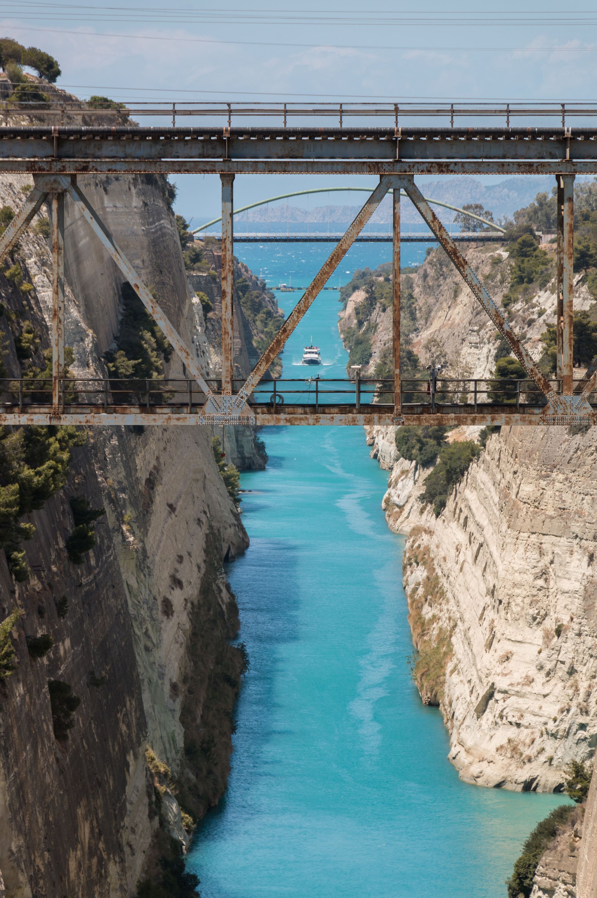 The Corinth Canal, a turquoise channel cut between sheer limestone walls, seen from the old bridge