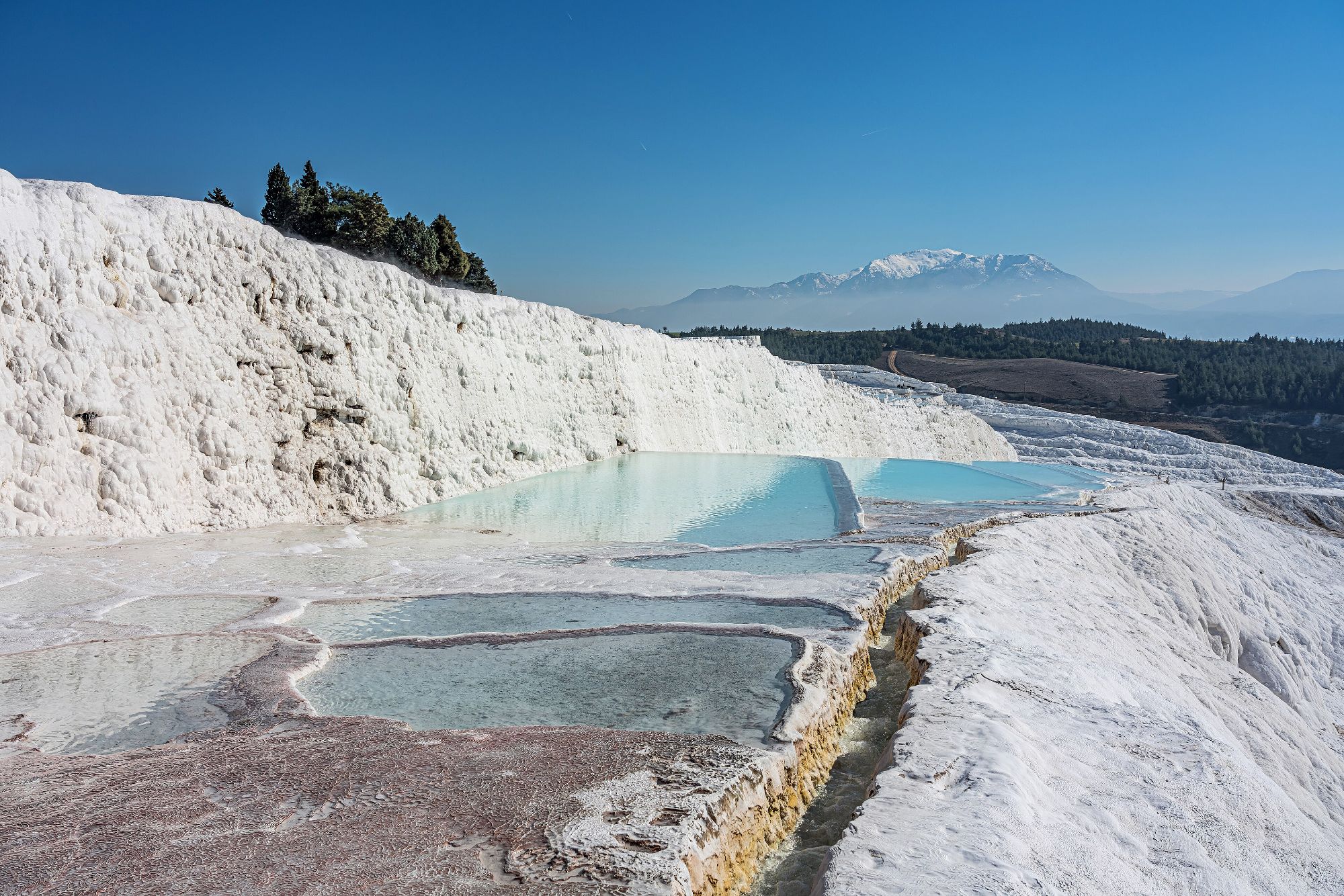 The white travertine terraces of Pamukkale, pools of pale blue water stepping down the hillside